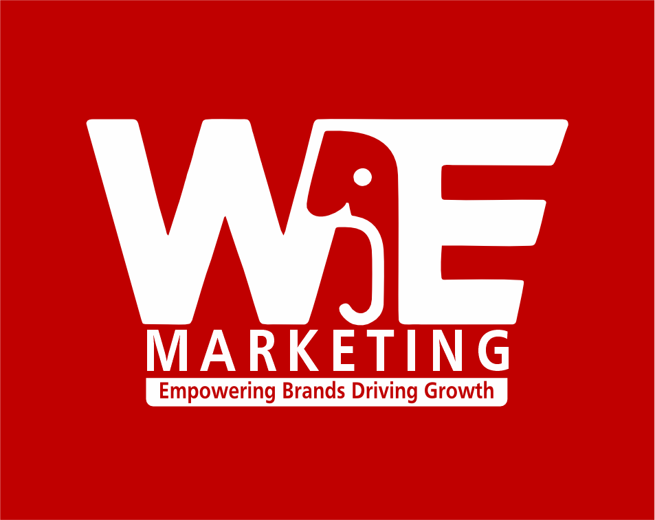 Two people sitting and talking in a modern office space, one woman and one man, smiling and looking at a notebook